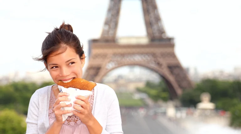 Woman tasting a crepe in front of the Eiffel Tower