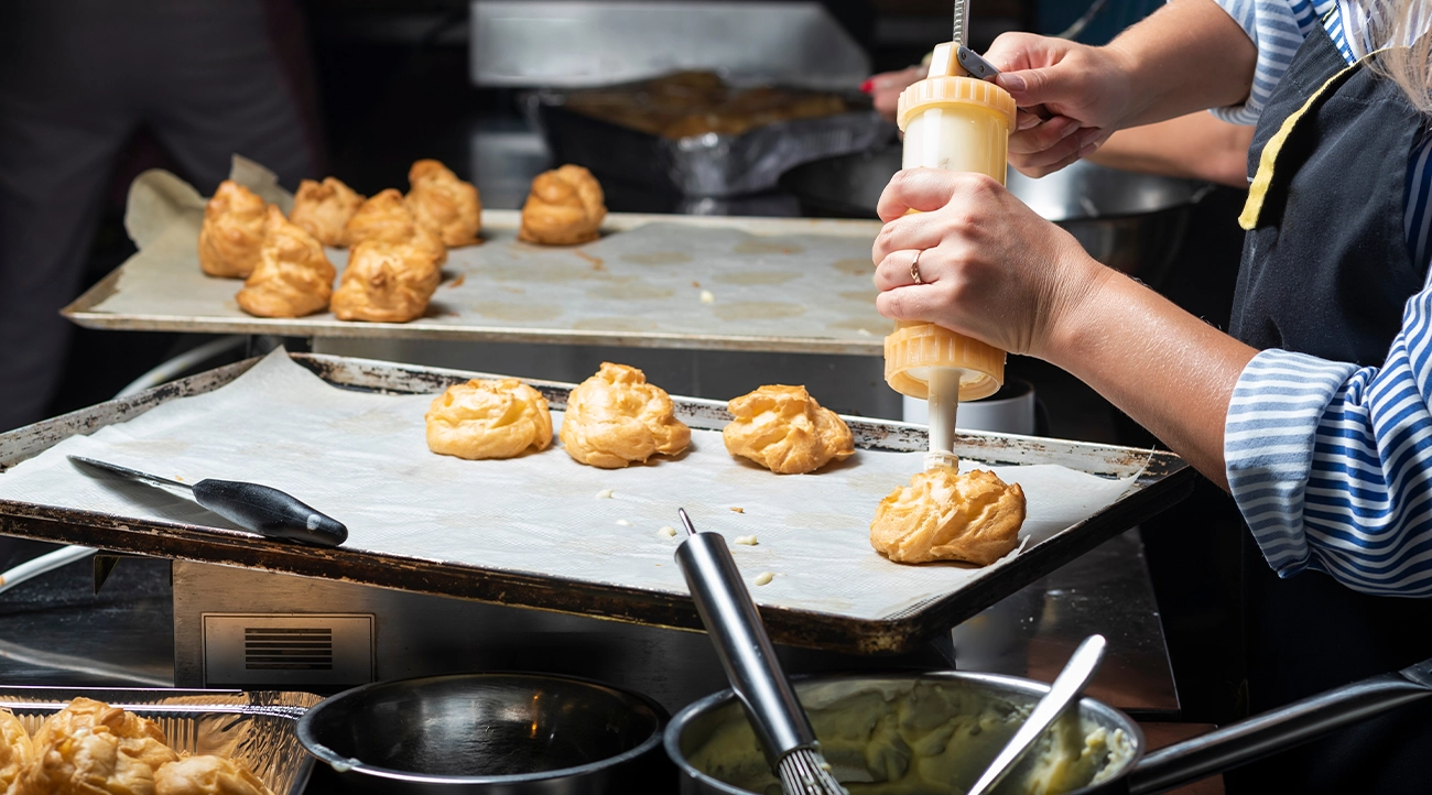 A cooking class participant fills a pastry product