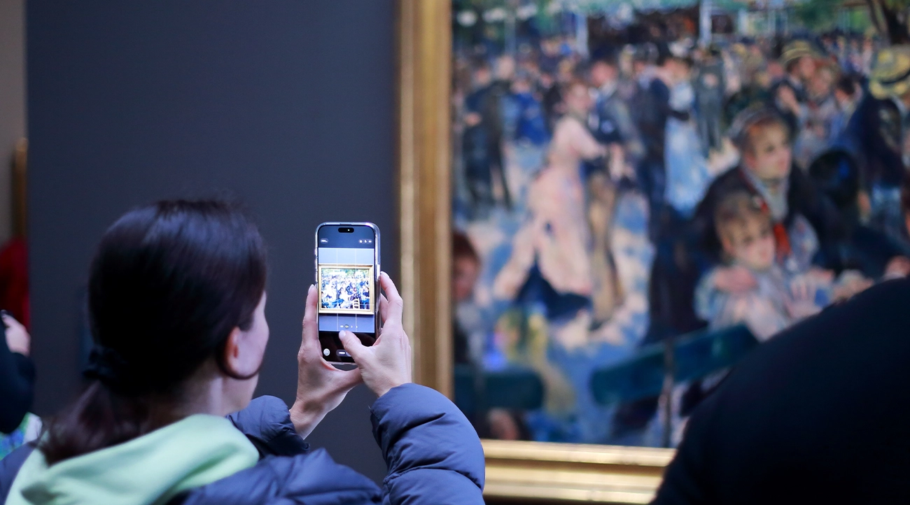 A tourist takes a picture of a painting at the Musée d'Orsay