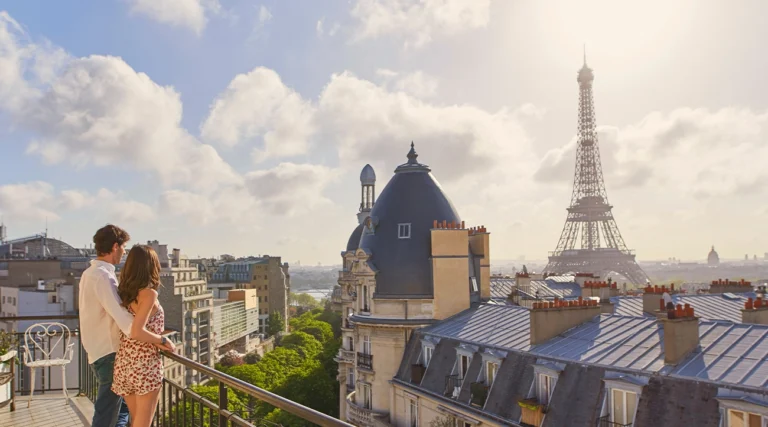 Couple looking out from hotel balcony observing the Eiffel Tower
