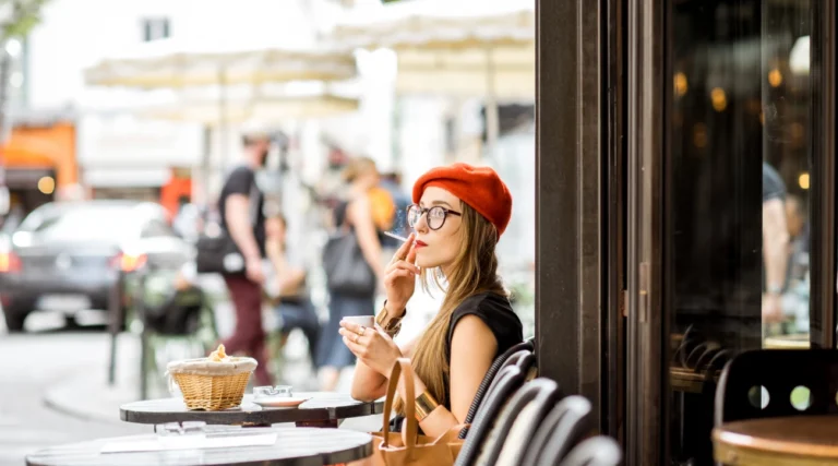 A woman smokes alone at a table in a Paris bar
