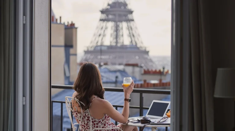 A woman enjoys juice on her hotel balcony facing the Eiffel Tower